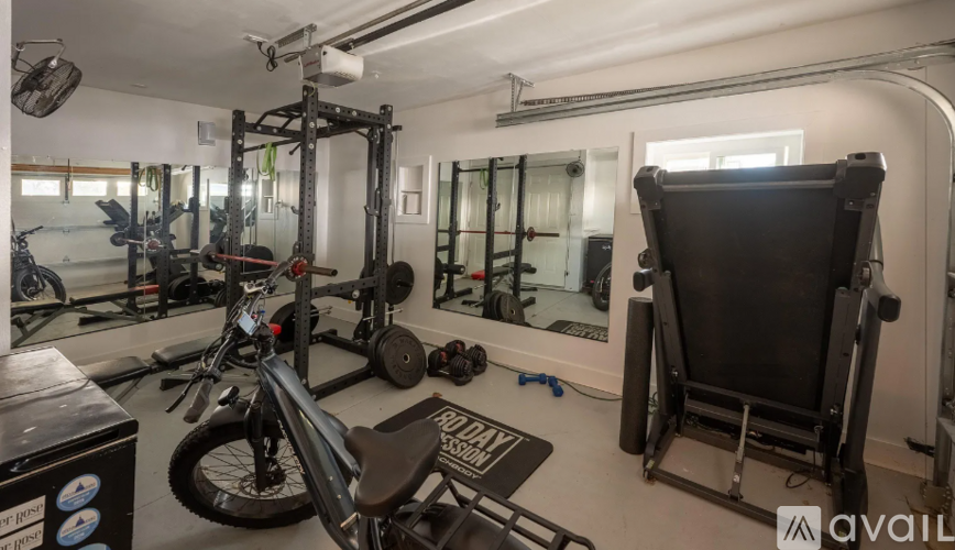A gym with a variety of equipment including a stationary bike, a rowing machine, and a squat rack.