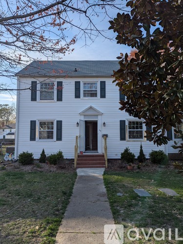 A white house with a brown door and steps leading to it.