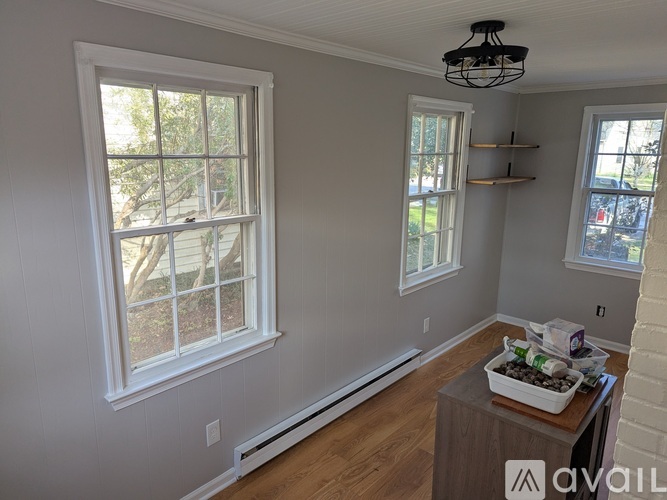 A room with a table in the middle and a window on the left.