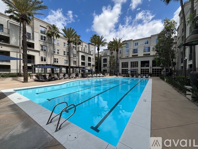 A swimming pool in front of a building with palm trees.
