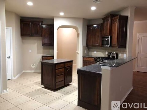 A kitchen with dark wood cabinets and a black countertop.