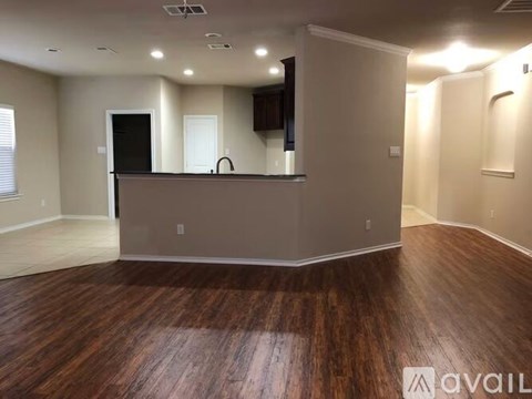A spacious room with wooden floors and a bar area.