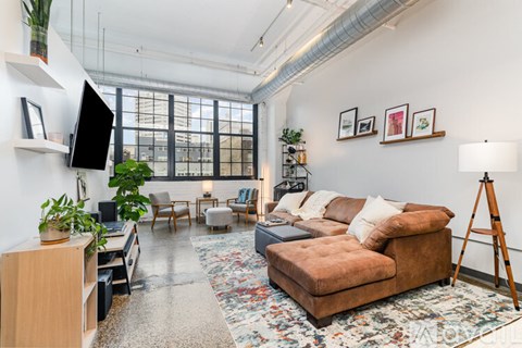 A living room with a brown couch and a wooden floor.