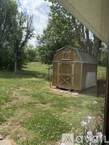 A wooden shed sits in a grassy field.