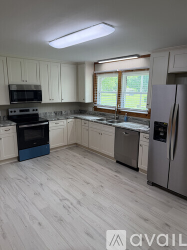 A kitchen with white cabinets and a wooden floor.