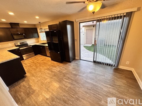 A kitchen with black appliances and wooden floors.