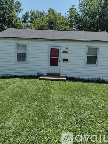 A white house with a red door and a brown roof.