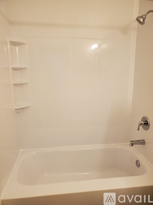 A white bathtub with a shower head and faucet.