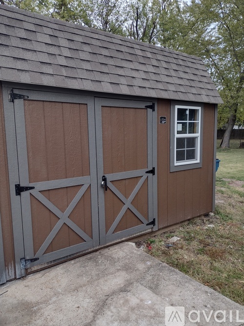A shed with a brown door and a grey roof.