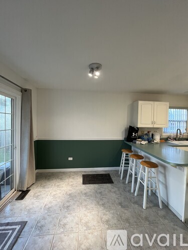 A kitchen with white cabinets and a green wall.