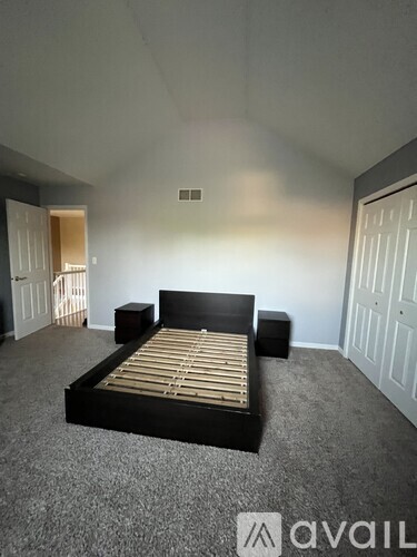 A bedroom with a bed, nightstand, and a carpeted floor.