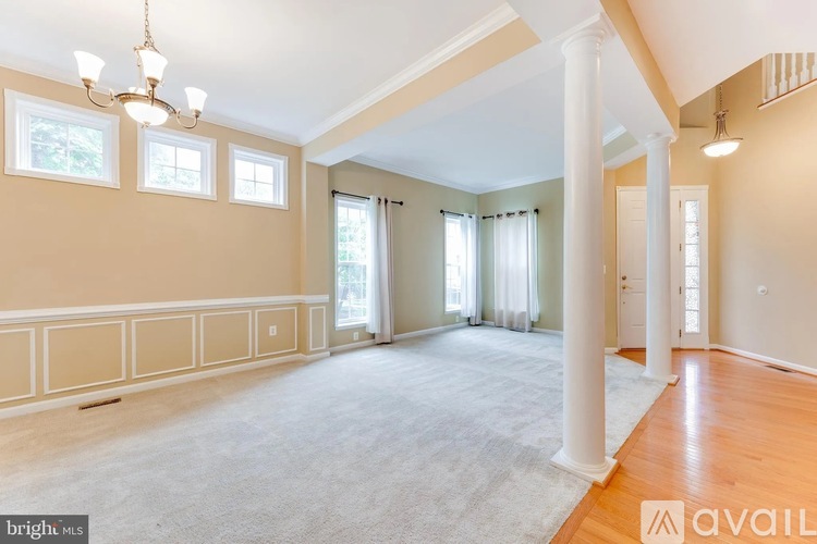 A spacious room with a carpeted floor, a chandelier, and a window with curtains.