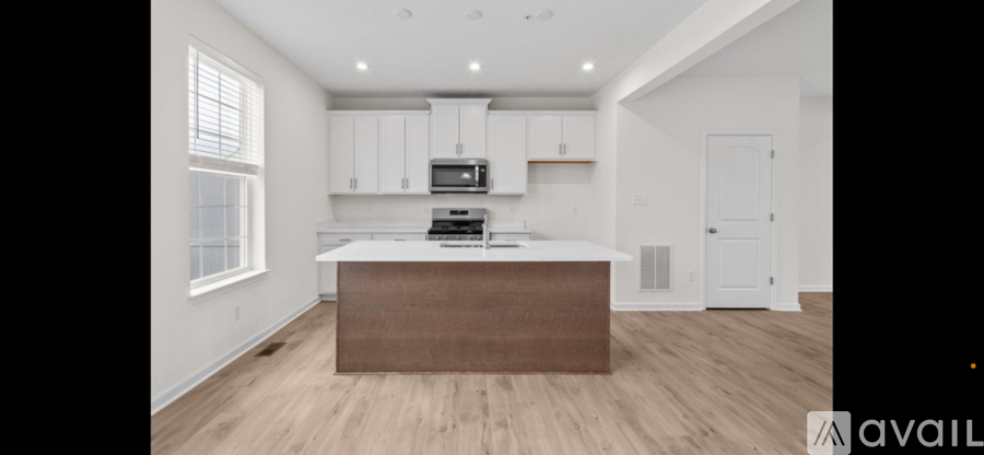 A kitchen with white cabinets and a brown island.