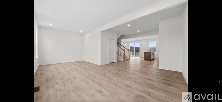 A spacious room with wooden flooring and white walls.