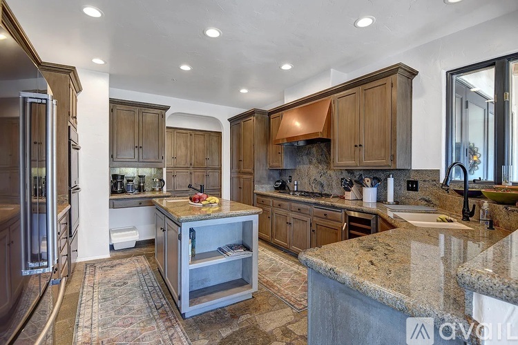 A kitchen with brown cabinets and granite countertops.