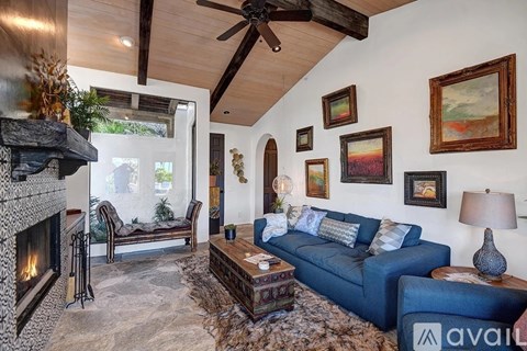 A living room with a blue couch and a fireplace.