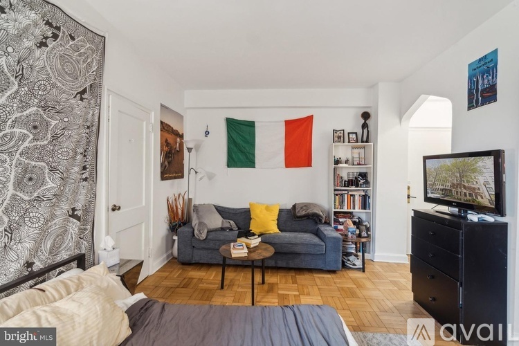 A living room with a grey couch, a coffee table, a bookshelf, and a television.