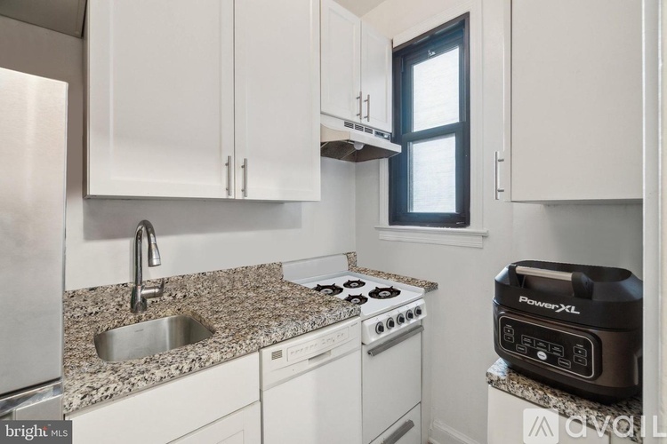 A kitchen with white cabinets and a granite countertop.