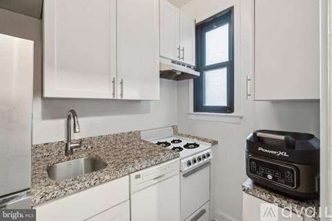 A kitchen with white cabinets and a granite countertop.