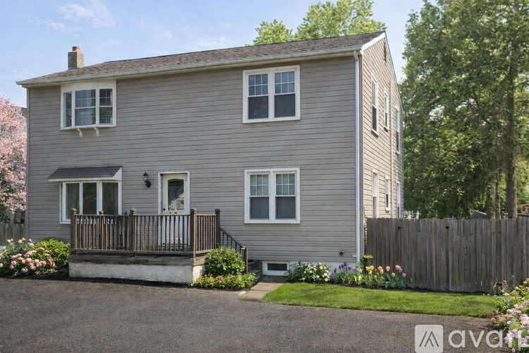 A grey house with a wooden fence and a small garden in front.