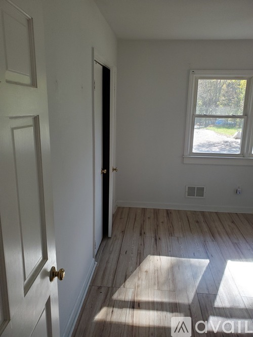 A room with a white door and a window letting in sunlight.