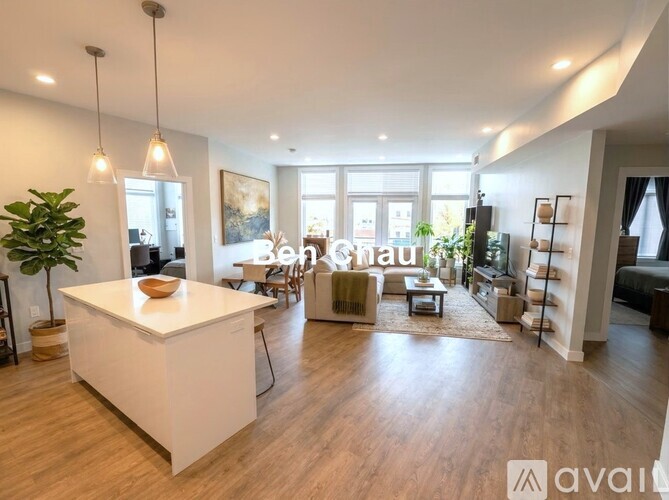 A spacious living room with a white kitchen island and hardwood floors.