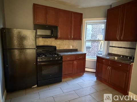 A kitchen with brown cabinets and black appliances.