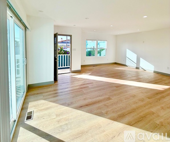 A spacious room with wooden flooring and a balcony with a railing.