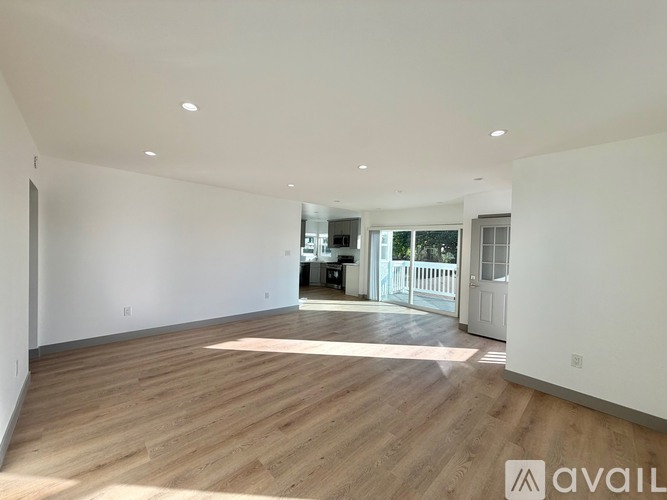 A spacious room with wooden flooring and white walls.