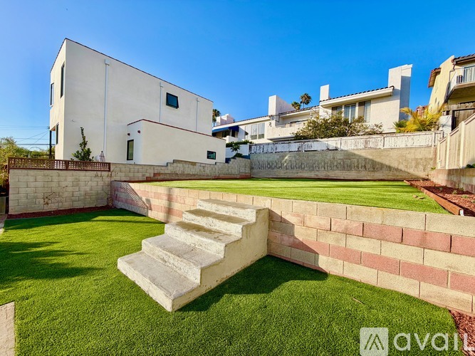 A white house with a green lawn and steps leading up to it.