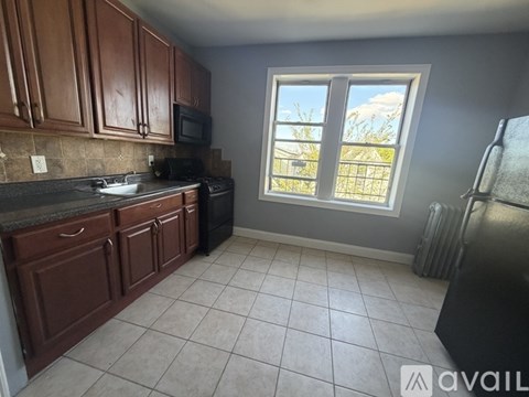 A kitchen with brown cabinets and a black stove top oven.
