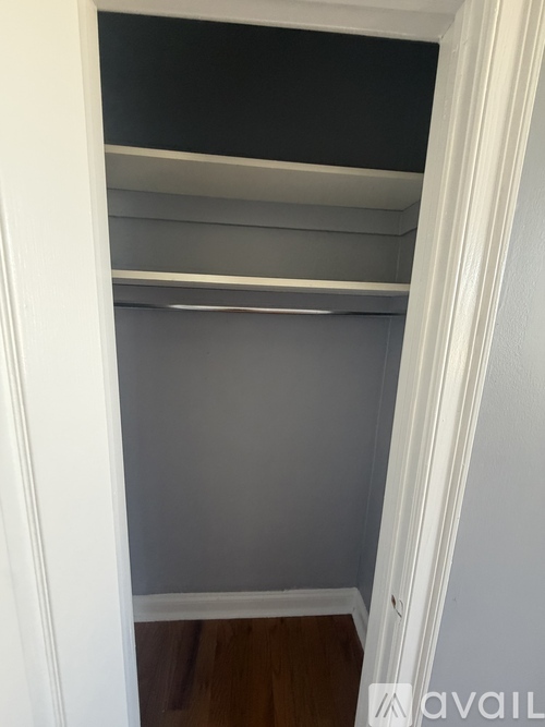 A white closet with a grey shelf and a white door.