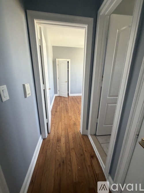 A hallway with a wooden floor and white walls.
