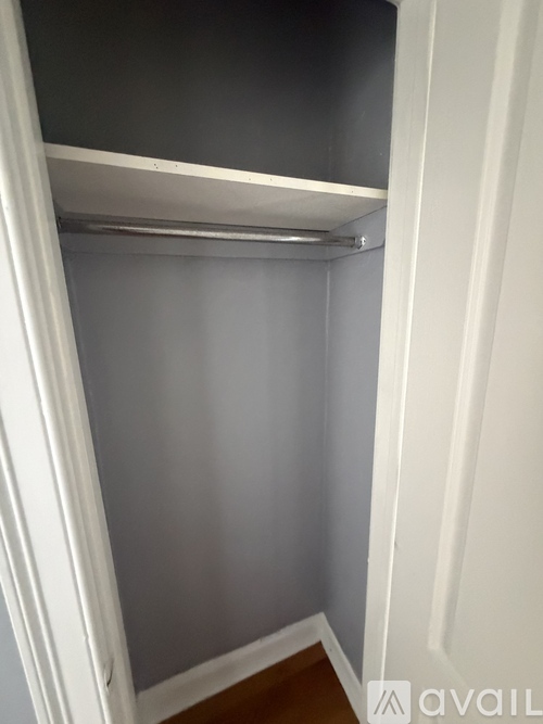 A white closet with a shelf and a white door.