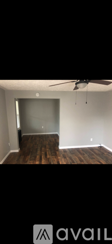 A room with a ceiling fan and wooden flooring.