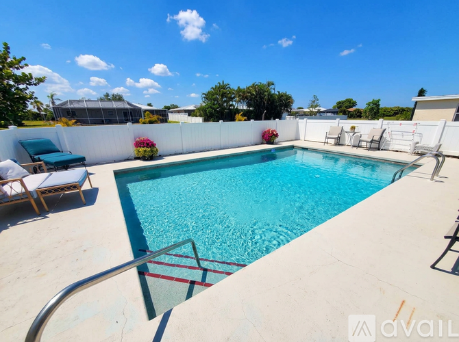 A pool with a metal railing and a white wall with flowers.