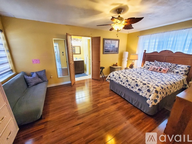 A bedroom with a bed, a couch, and a ceiling fan.