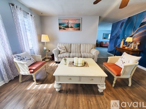 A living room with a white sofa, a white coffee table, and a painting on the wall.