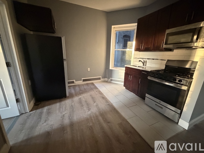 A kitchen with a black fridge, stove, and microwave.