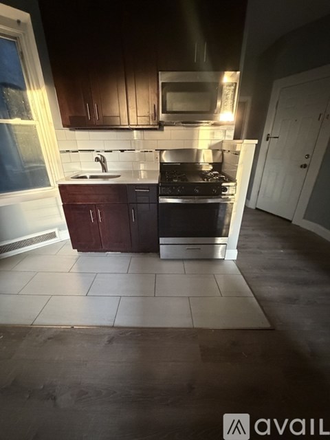 A kitchen with dark brown cabinets and a black stove top oven.