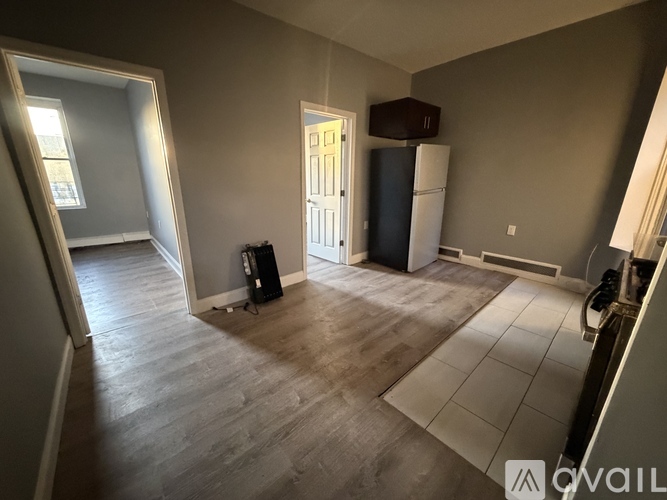 A room with a white door, a black fridge, and a black speaker on the floor.
