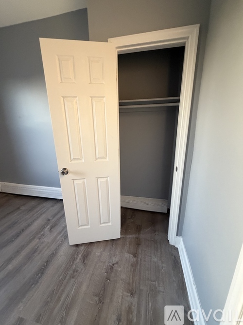 A white door is open to a room with grey walls.