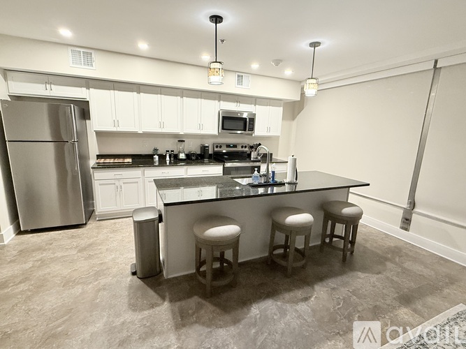 A kitchen with a refrigerator, stove, and bar stools.