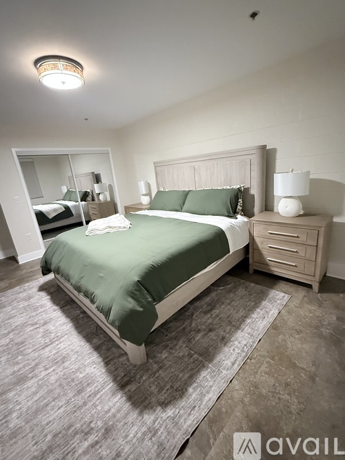 A bedroom with a bed, nightstand, and lamp.