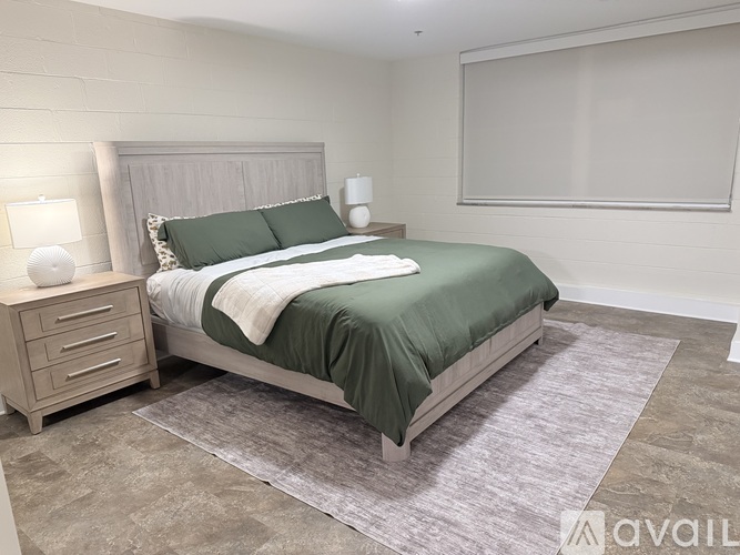 A bedroom with a bed, nightstand, and lamp.