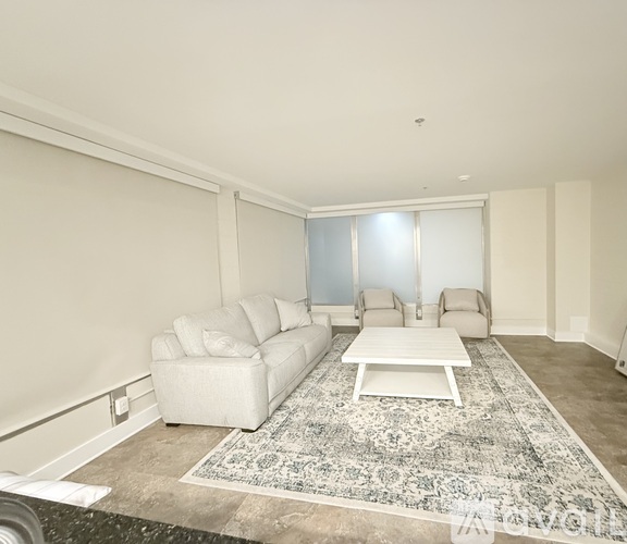A living room with a white couch, two chairs, and a rug.