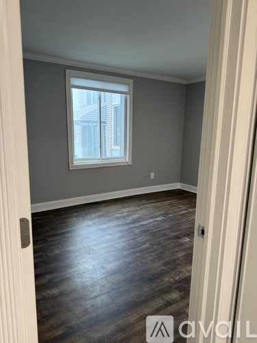 A room with a window and wooden flooring.
