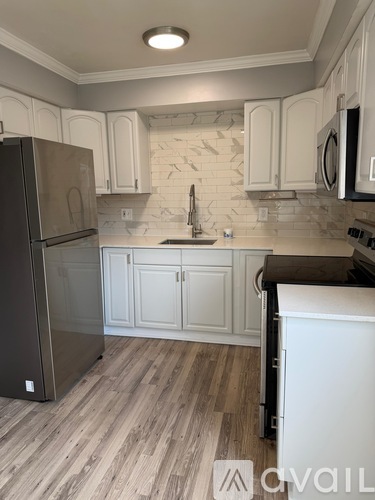 A kitchen with a refrigerator, cabinets, and a countertop.