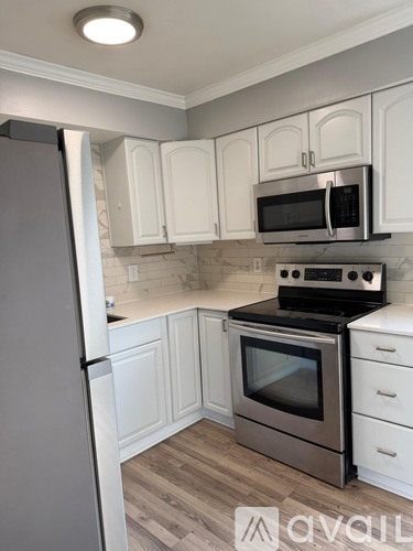 A kitchen with white cabinets and a stainless steel refrigerator.