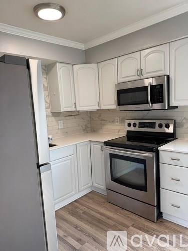 A kitchen with white cabinets and a stainless steel refrigerator.